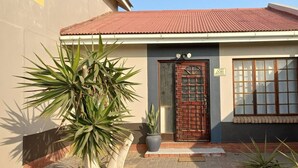 A two-story building with a red-tiled roof, a brick entrance, and a large window with multiple panes. - Lovely 1 bedroom Loft in the Heart of Walvisbay. (Walvis Bay)
