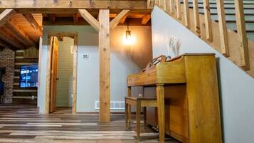 Una habitación amplia con una escalera de madera, un piano y un televisor en la pared.