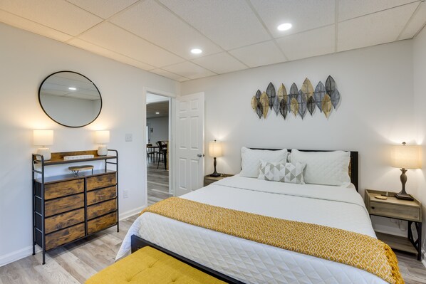 A bedroom with a bed, bedside tables, a dresser, a mirror, and wall art.