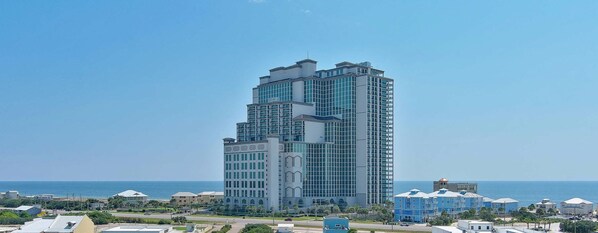 A high-rise hotel with multiple floors, large windows, and a view of the sea.