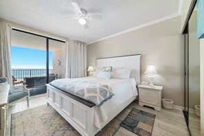 A bedroom with a bed, bedside tables, a nightstand, a chair, a desk, a ceiling fan, and a view of the ocean. - BEACHFRONT CONDO, MULTIPLE POOLS, PRIVATE BALCONY! (Orange Beach)