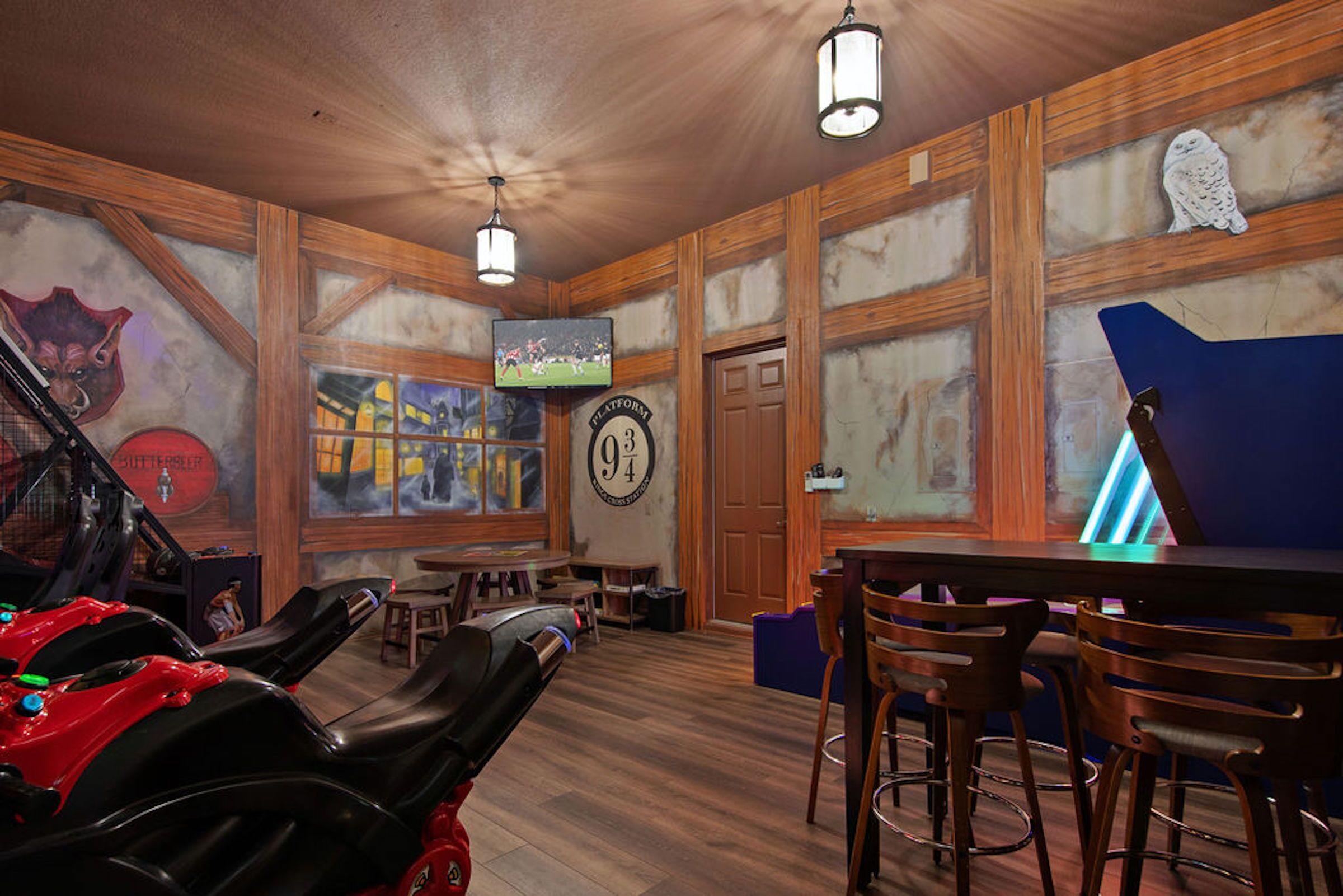 Un espace bar avec des murs en bois, un téléviseur fixé au mur et un panneau néon bleu.
