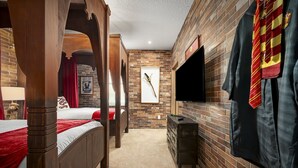 Une chambre à coucher avec un lit à baldaquin, un mur en briques, un téléviseur à écran plat et une armoire.