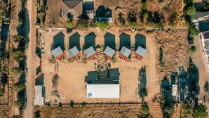 Vue aérienne d’une propriété comprenant plusieurs bâtiments, dont une grande structure centrale et plusieurs bâtiments plus petits dotés de toits rouges.