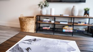 A magazine on a wooden table with a bookshelf in the background. - Revylation by Revelstoke Vacations (Revelstoke)
