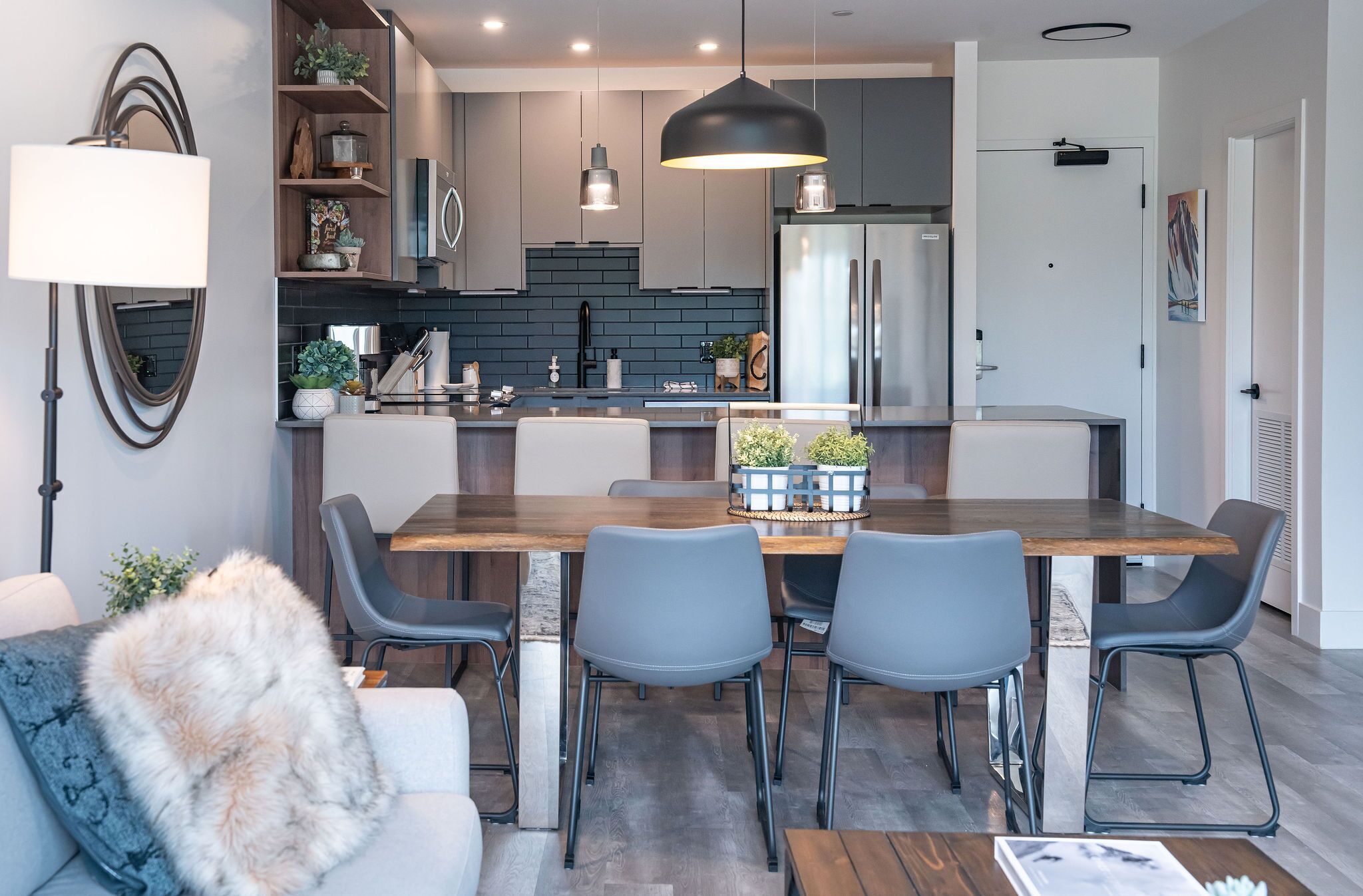 A modern kitchen with a central island, grey chairs, and a dining table.