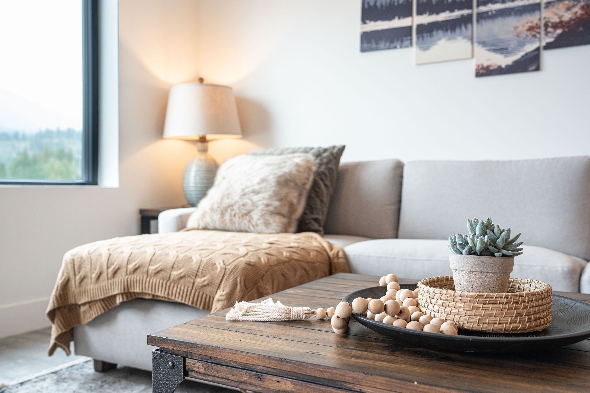 A cozy living room with a sofa, a lamp, a potted plant, and a tray with decorative items.
