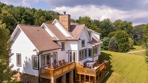 Une maison à deux étages avec une terrasse en bois et une cheminée en pierre.