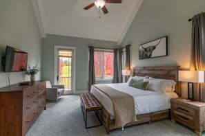 A bedroom with a large bed, a wooden headboard, a bench, a dresser, and a ceiling fan. - Mountain Top at Linville Falls: Amazing Views! Hot Tub! Pet Friendly! Near Linville Falls Winery! (Newland)