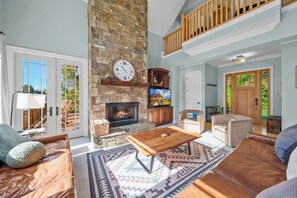 A spacious living room with a stone fireplace, a television, and comfortable seating. - Mountain Top at Linville Falls: Amazing Views! Hot Tub! Pet Friendly! Near Linville Falls Winery! (Newland)