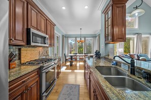 A modern kitchen with wooden cabinets, stainless steel appliances, and a large island with a sink.