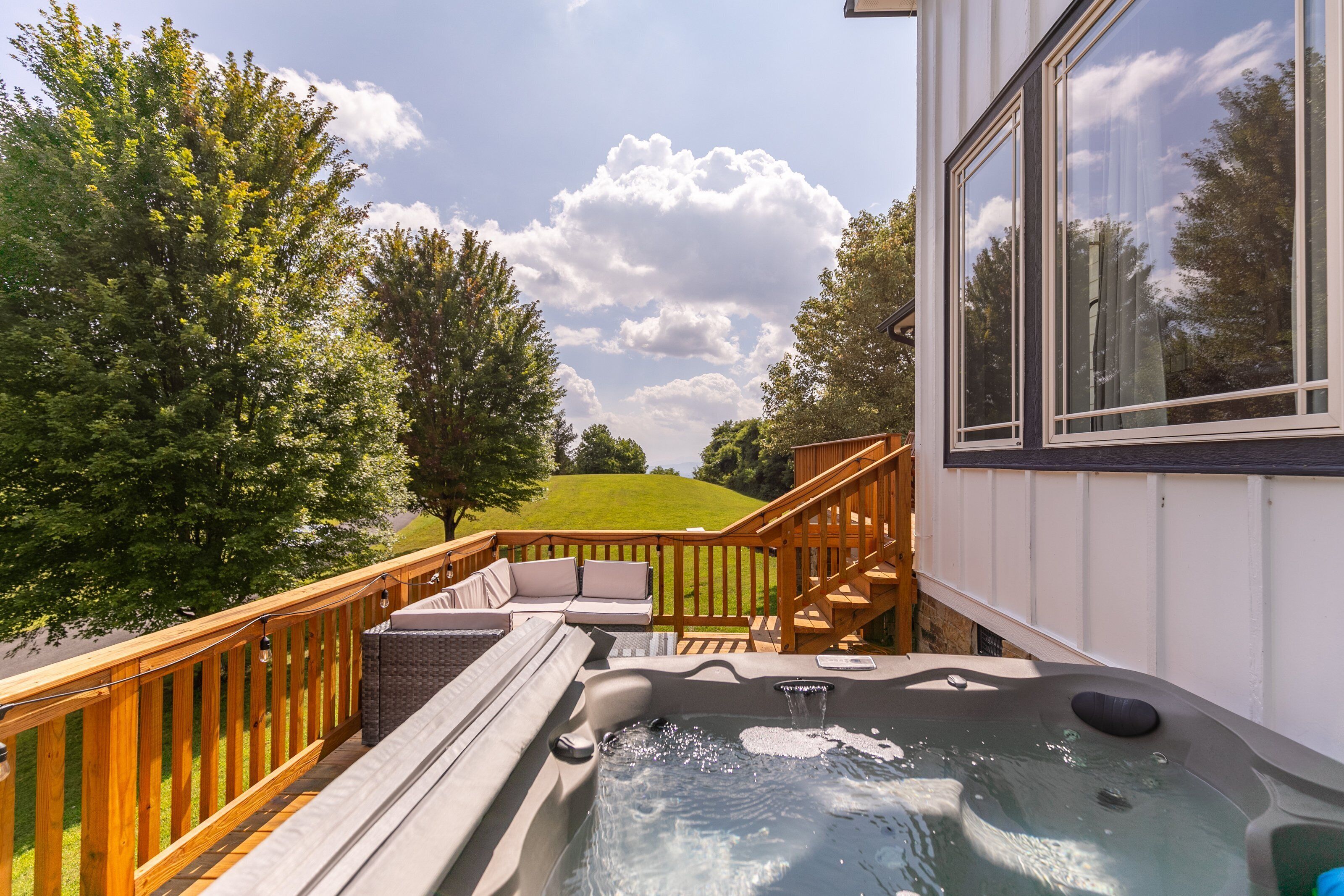 Soak under open skies with a bubbling hot tub, deck seating, and a sweeping green lawn just steps away.