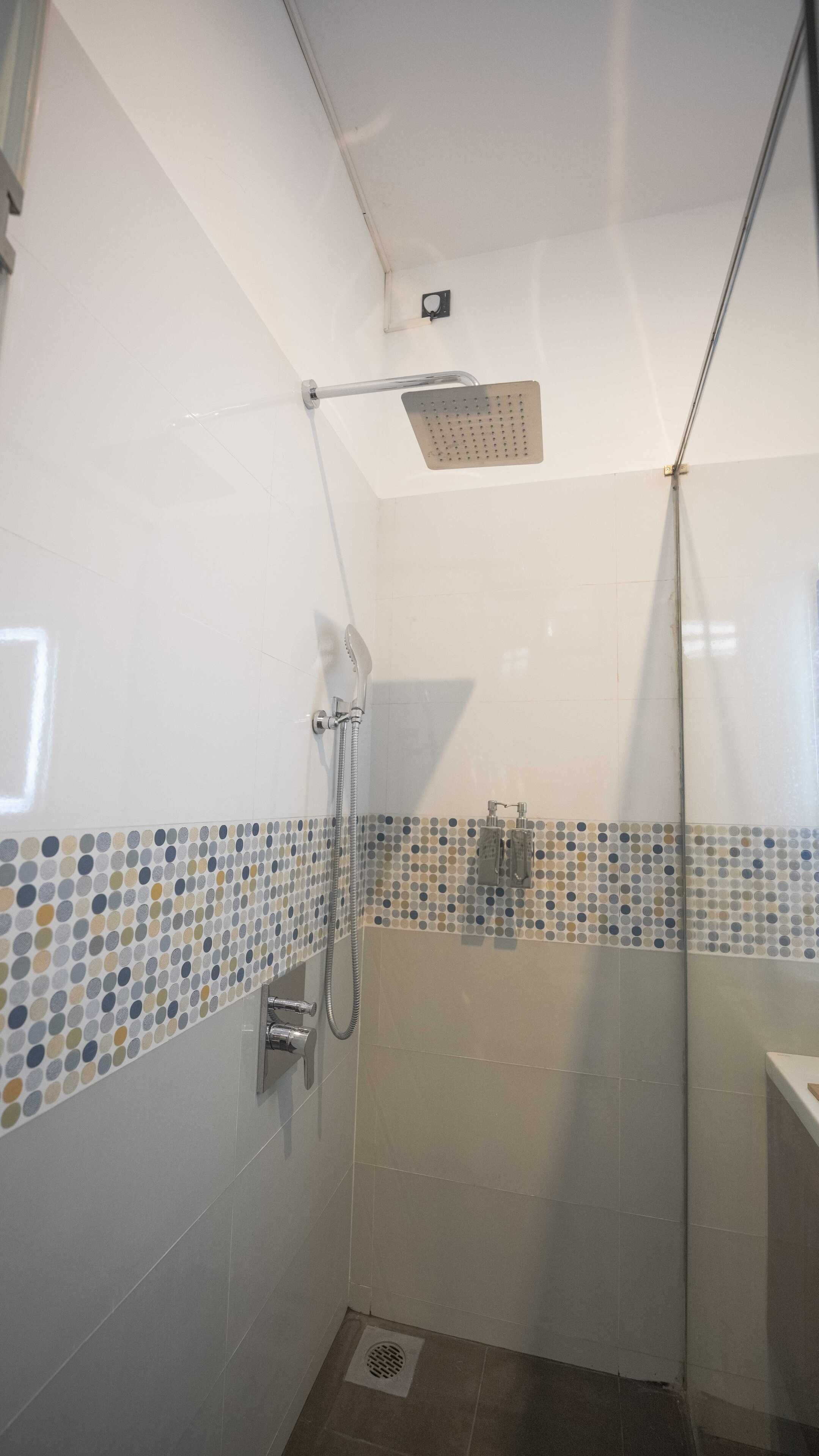A small, enclosed shower area with a handheld showerhead, a fixed showerhead, and a tiled floor.