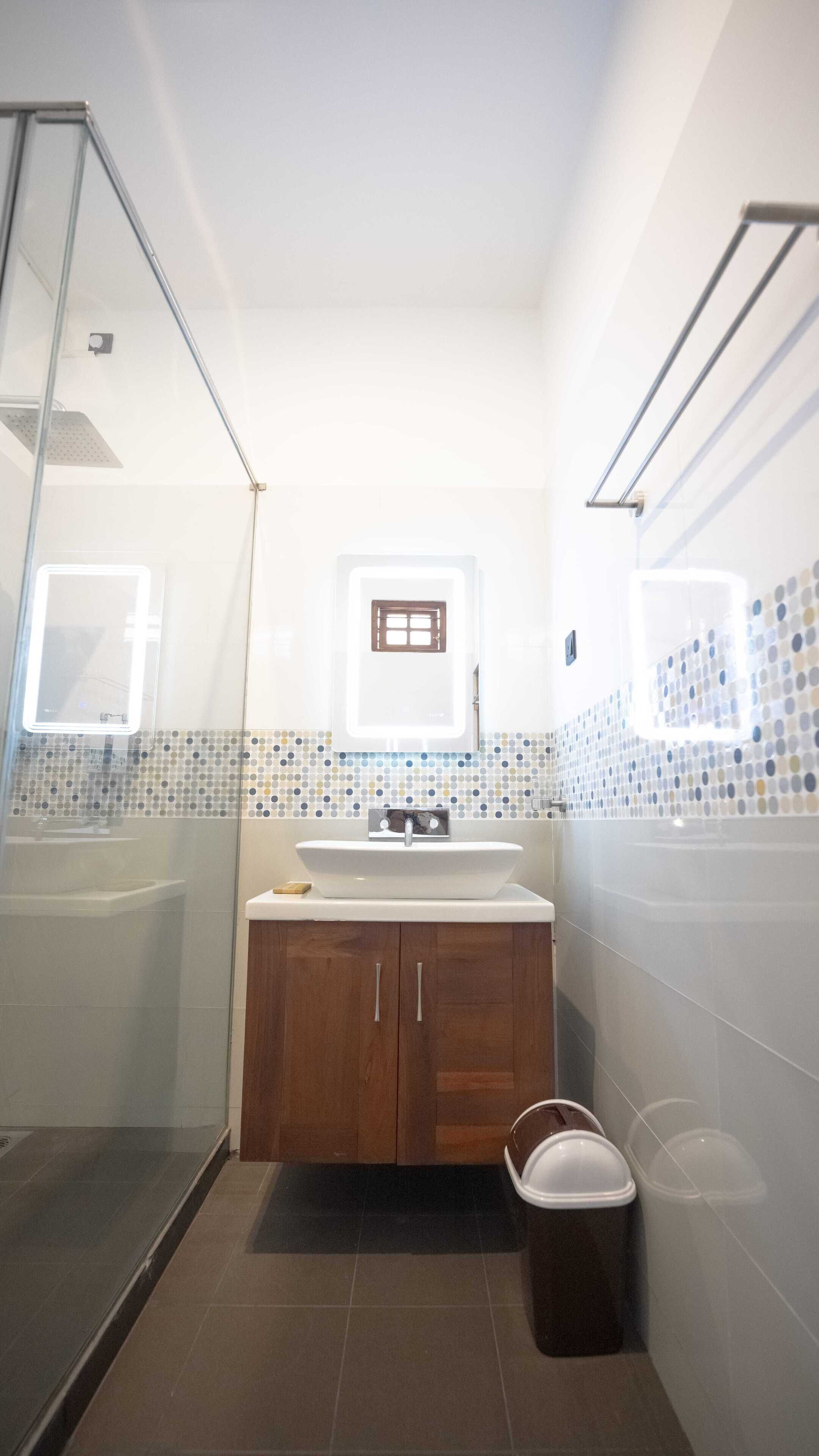 A bathroom with a glass shower enclosure, a white sink with a mirror above it, and a tiled backsplash.