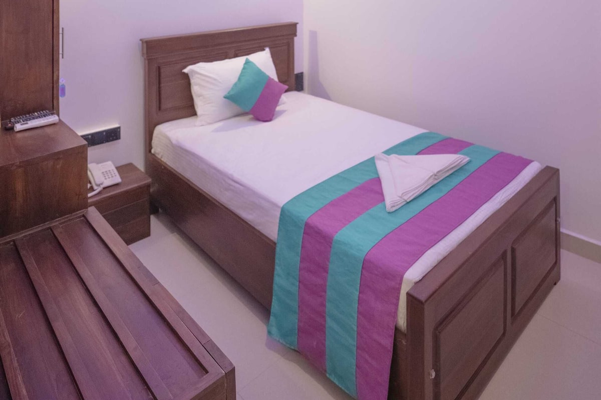 A modern bedroom with a wooden bed, a bedside table, a nightstand, and a ceiling light fixture.