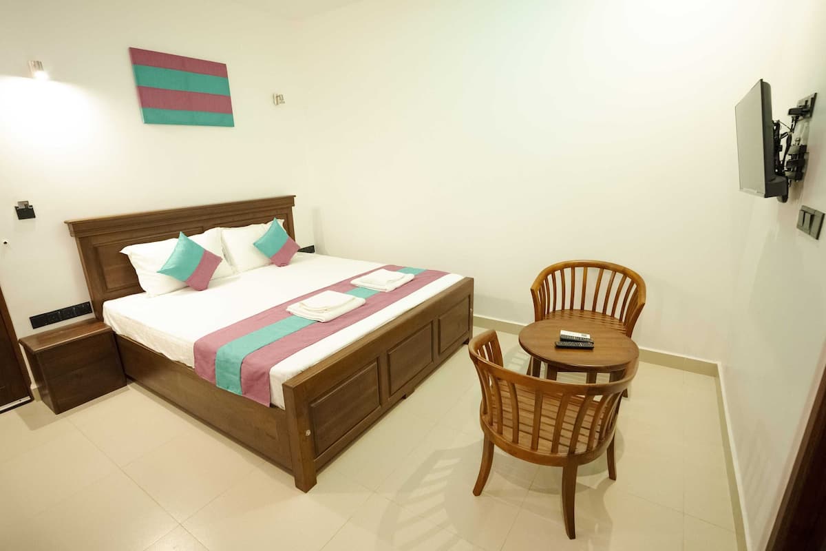 A neatly arranged bedroom with a bed, bedside table, and a small round table with a chair.