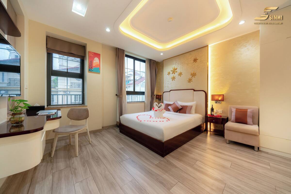 Quarto de hotel moderno com uma cama, uma escrivaninha, uma cadeira e um pequeno sofá.