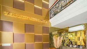 A modern lobby with a reception desk, seating area, and a staircase.