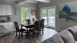 A dining area with a table and chairs, a kitchen with white cabinets, and a painting on the wall. - Spacious home, 12 miles from Nubs Nob, Harbor Springs surrounded by forest. (Alanson)