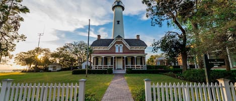 A lighthouse museum with a brick building and a tall white tower.