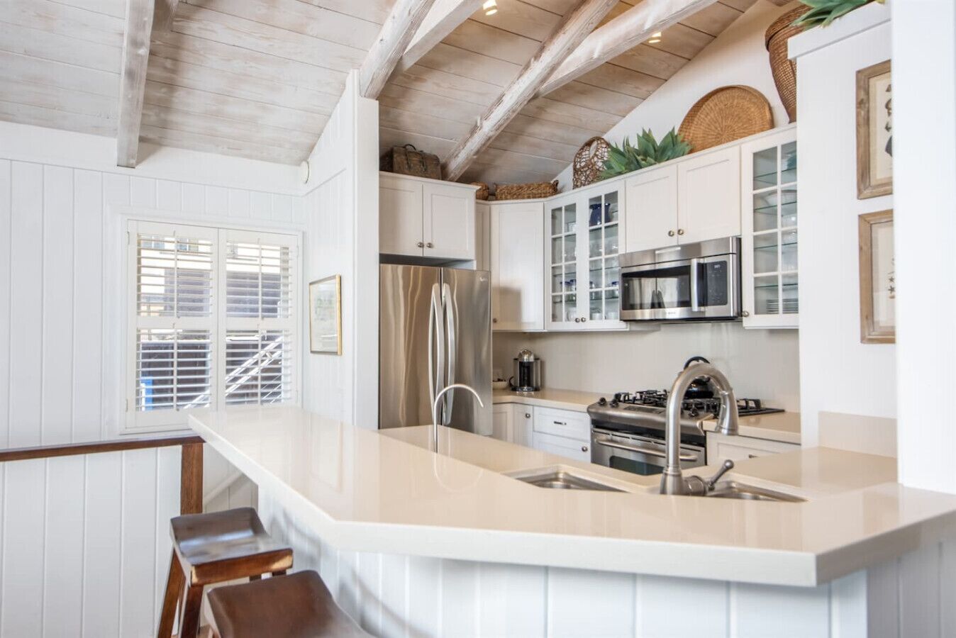 A modern kitchen with white cabinetry, stainless steel appliances, and a large island with bar stools.