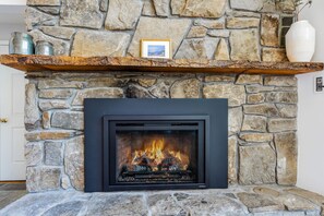 A stone fireplace with a black frame, a shelf above it, and a framed picture.