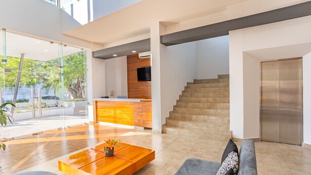 A spacious living area with a modern kitchen, a staircase, and a large window overlooking greenery. - WinDay Veracruz Hotel Express (Veracruz)