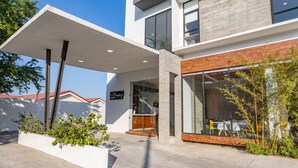 A modern building with a flat roof, large windows, and a covered entrance area with outdoor seating. - WinDay Veracruz Hotel Express (Veracruz)