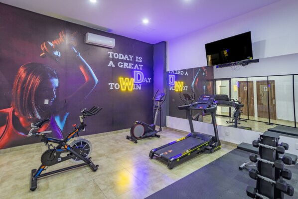 A gym with exercise equipment, motivational wall art, and a TV.