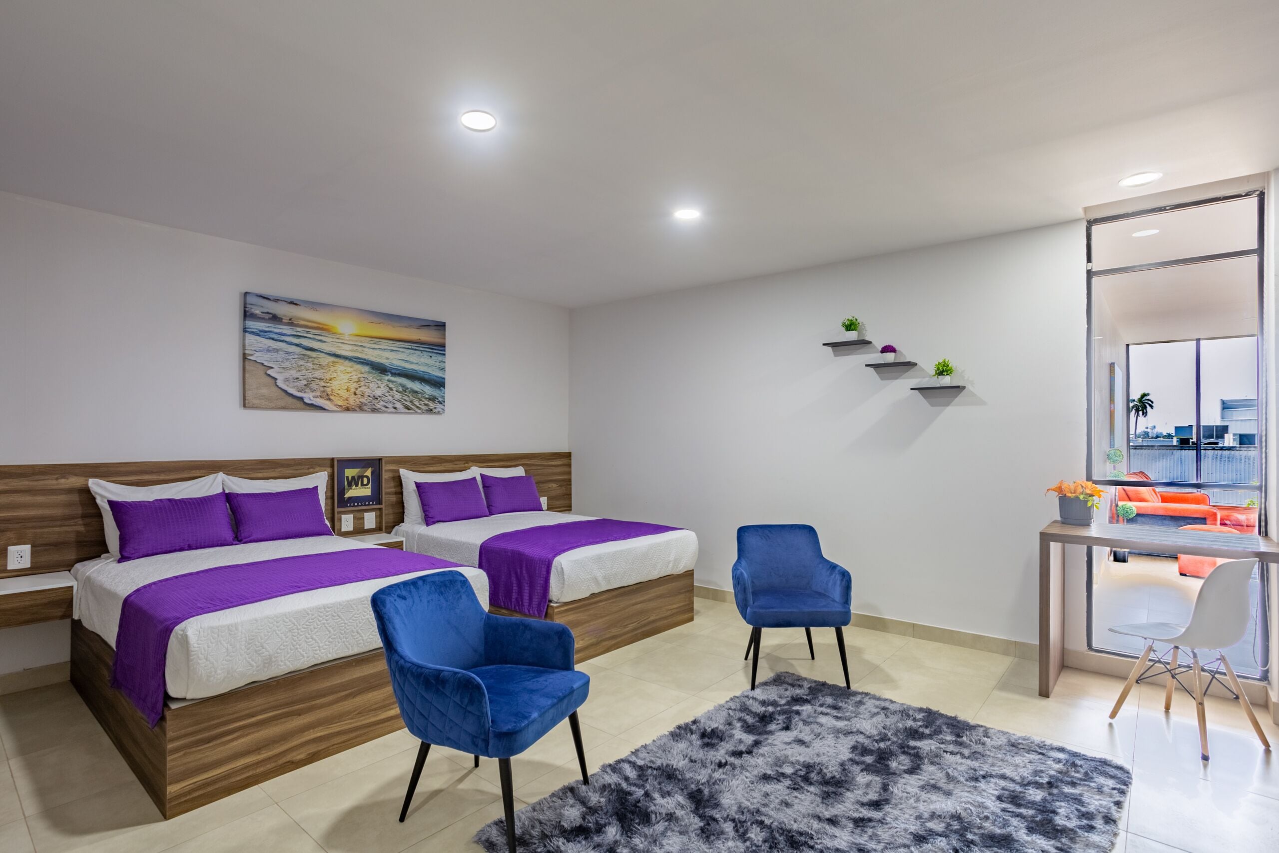 A modern hotel room with two beds, a desk, and a chair.