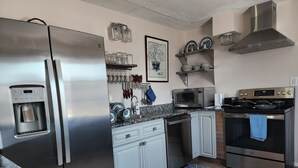 Een moderne keuken met roestvrijstalen apparatuur, een waterdispenser, een magnetron en een fornuis.
