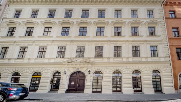 Un immeuble à étages, de style architectural classique, caractérisé par une façade symétrique avec des fenêtres régulièrement espacées et des moulures décoratives.