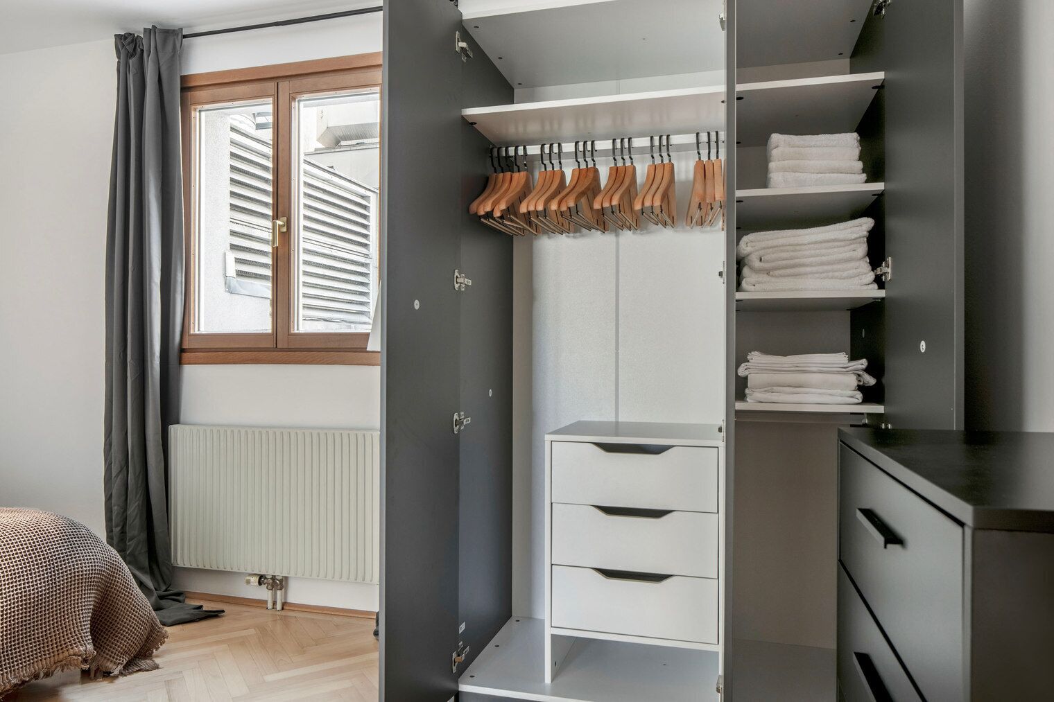 Et moderne soveværelse med indbygget skab, radiator og et vindue med persienner.