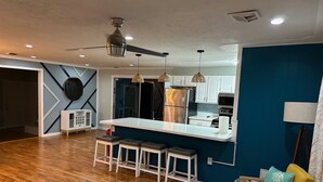 A modern kitchen with a central island, bar stools, pendant lighting, and a ceiling fan. - Private one level home with pool near Anna Maria Island (Bradenton)