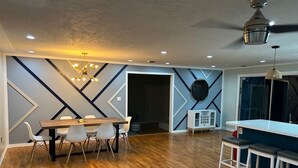 A modern dining area with a wooden table and chairs, a white cabinet, and a ceiling fan. - Private one level home with pool near Anna Maria Island (Bradenton)