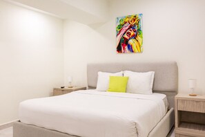 Ein modernes Schlafzimmer mit einem großen Bett, zwei Nachttischen und einem farbenfrohen, abstrakten Gemälde an der Wand.