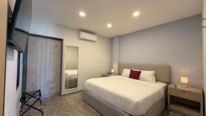 Un dormitorio moderno con una cama grande, mesitas de noche, un armario y un equipo de aire acondicionado.