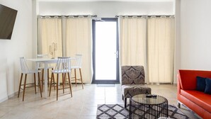 Un salon moderne comprenant un coin repas, un canapé, une table basse et un téléviseur fixé au mur.