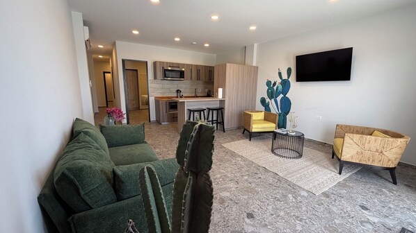 Una sala de estar moderna con un sofá verde, una escultura de cactus y un televisor de pantalla plana montado en la pared.