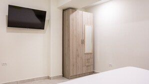 Une chambre à coucher comprenant un lit, une armoire et un téléviseur à écran plat fixé au mur.