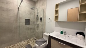 Un baño moderno con ducha, inodoro y lavamanos.