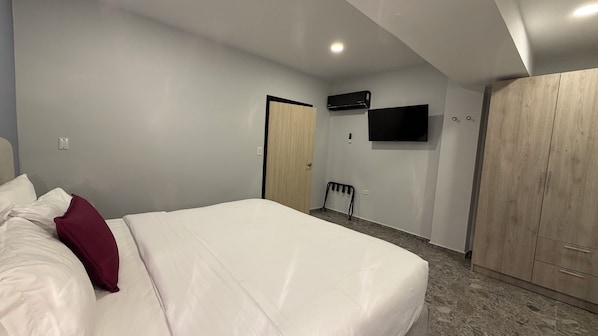 A bedroom with a bed, a wardrobe, a TV, and a radiator. - Bushiri's Long Life Building-2BD/1BA APT-Sleeps 4 (Noord)