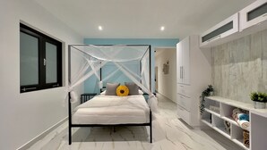 Un dormitori modern amb un llit amb cortines, una finestra gran i un armari encastrat.