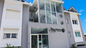 Un edificio de varios pisos con fachada gris, ventanas grandes y un letrero que dice "Sky Marine Residence".