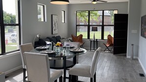 A modern dining area with a glass table, black chairs, and a ceiling fan. - Newly Renovated Condo's (Detroit)