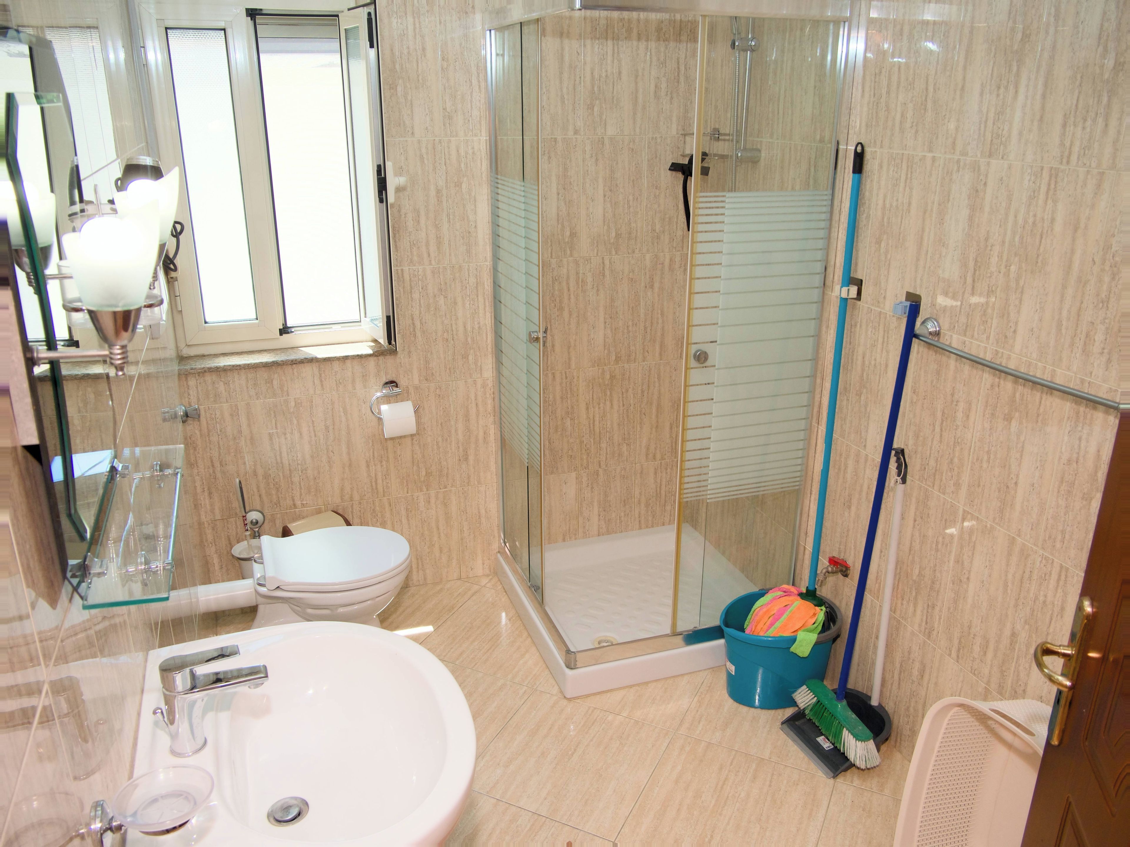 A bathroom with a glass-enclosed shower, a sink, a toilet, and a mirror.