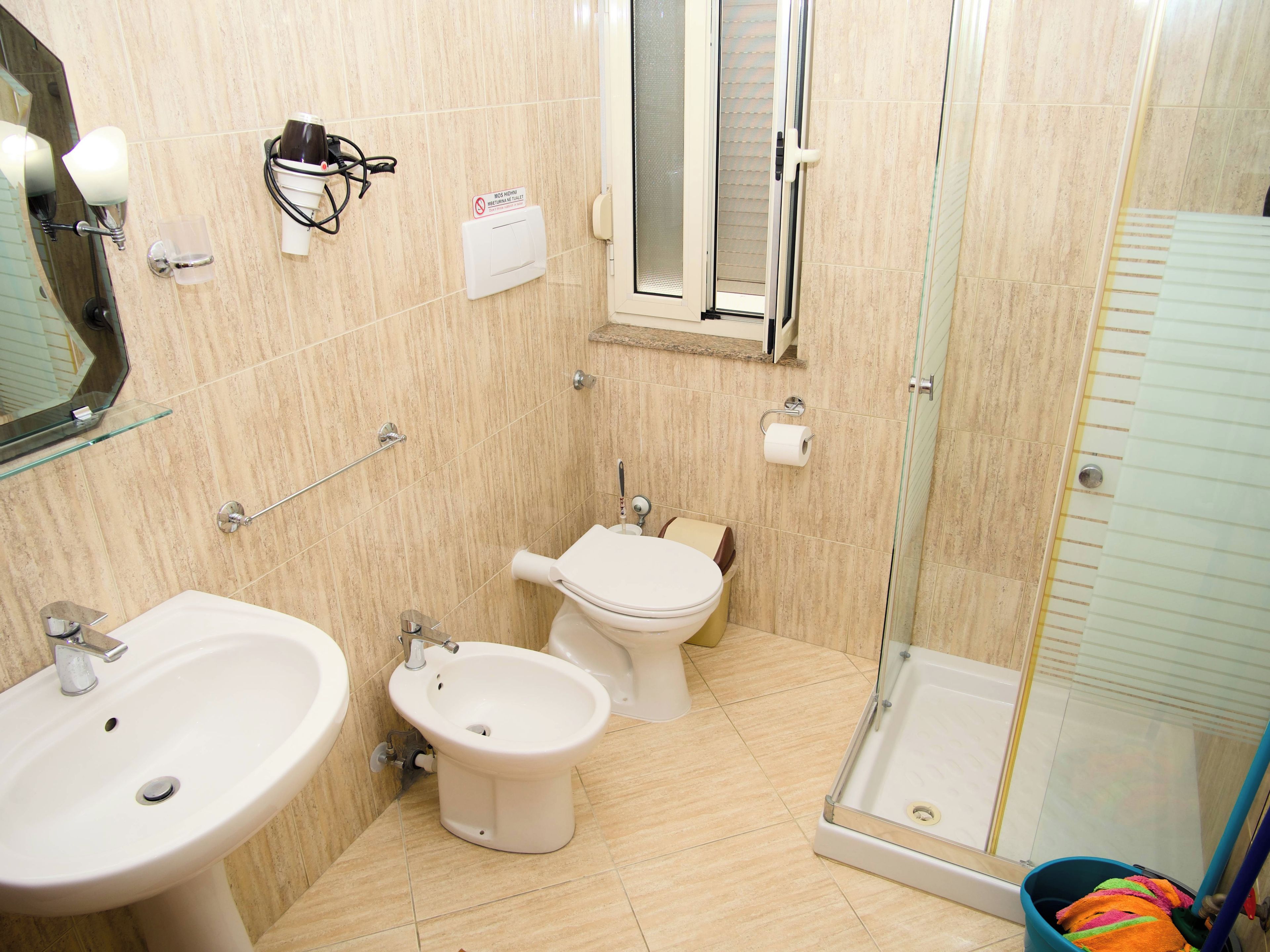 Een badkamer met een wastafel, bidet, toilet en douchecabine.