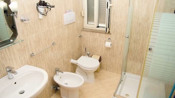 Een badkamer met een wastafel, bidet, toilet en douchecabine.