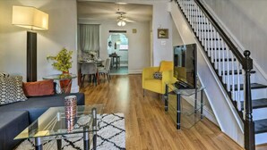 Ein modernes Wohnzimmer mit Sofa, Couchtisch und Fernseher. Eine Treppe führt zu einer weiteren Ebene.