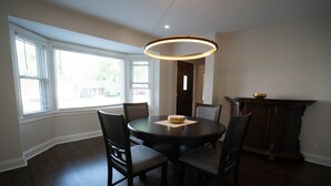 Una sala da pranzo con un tavolo rotondo, quattro sedie, un lampadario e un armadio in legno scuro.